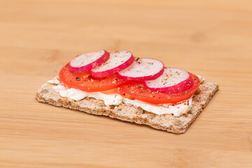 Whole Grain Crispbread with Tomato, Cream Cheese and Radish on Bamboo Cutting Board. Easy Breakfast. Quick and Healthy Sandwiches. Crispbread with Tasty Filling. Healthy Dietary Snack