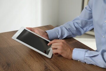 Businessman using tablet at wooden table, closeup. Modern technology