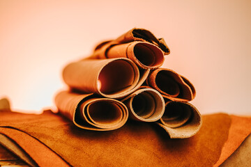  brown leather pieces and rolls set against an orange-hued background.materials for making...