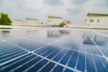 A close up of solar panels with a worker blurred in the background. The focus on the panels emphasizes the importance of renewable energy technology and solar power installations.