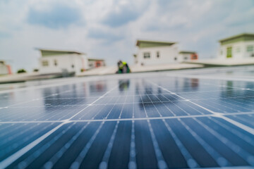 A close up of solar panels with a worker blurred in the background. The focus on the panels emphasizes the importance of renewable energy technology and solar power installations.