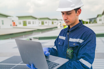 A worker in protective gear uses a laptop while inspecting solar panels on a rooftop. The image emphasizes the use of technology in managing renewable energy systems and solar power installations.
