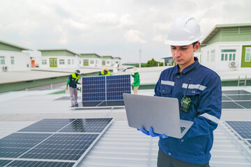 A worker in protective gear uses a laptop while inspecting solar panels on a rooftop. The image emphasizes the use of technology in managing renewable energy systems and solar power installations.