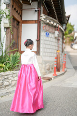 Fototapeta premium A 9-year-old Korean girl wearing a hanbok is walking through the historic streets of Gyedong-gil, Jongno District, Seoul, Korea.