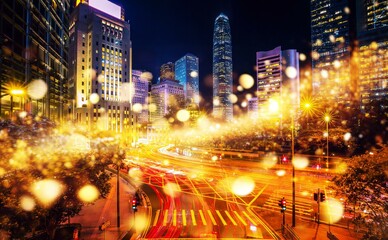 A night view of a busy street in Hong Kong, China with tall skyscrapers and bright lights.