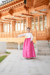 Obraz premium A 9-year-old Korean girl wearing a hanbok is performing a traditional dance in front of a traditional building in the historic town of Gyedong-gil, Jongno District, Seoul, Korea.