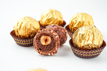 Sweet chocolate balls is made. Chocolate candy in gold wrapper on white background