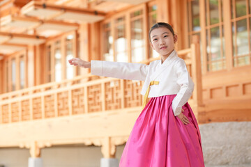 A 9-year-old Korean girl wearing a hanbok is performing a traditional dance in front of a traditional building in the historic town of Gyedong-gil, Jongno District, Seoul, Korea.