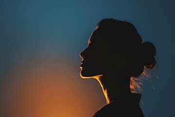 A woman's silhouette stands against a beautiful sunset sky, creating a dramatic and artistic image.