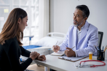 Senior doctor explaining diagnosis to young female patient during medical consultation