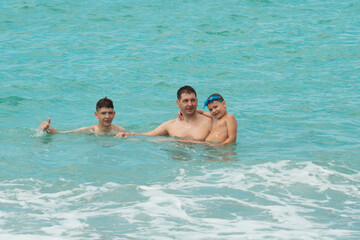 Father and sons swim in the turquoise sea