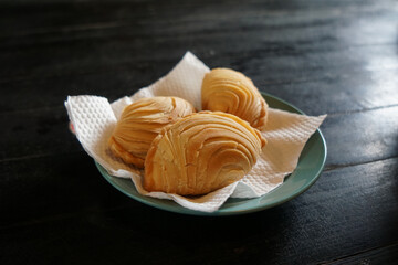 A plate of Malaysian deep fried curry puff or epok-epok isolated on dark background. Also known as Karipap Pusing.