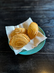 A plate of Malaysian deep fried curry puff or epok-epok isolated on dark background. Also known as Karipap Pusing.