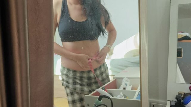 An overweight woman is squeezing her belly and feeling bad about her excess fat.