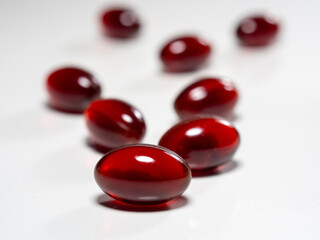 Krill oil capsules on white background. Translucent red softgel capsules of antarctic krill oil. Cardiovascular health. Nutritional supplement with valuable substances