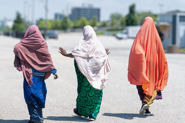 three unrecognizable Muslim friends talking and walking on the streets on a sunny day