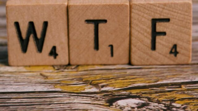 Dolly move on block letters WTF over wood background for creative message