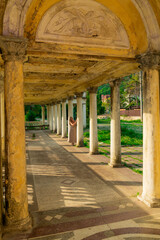 Stylish woman in an abandoned building with columns in a brown dress