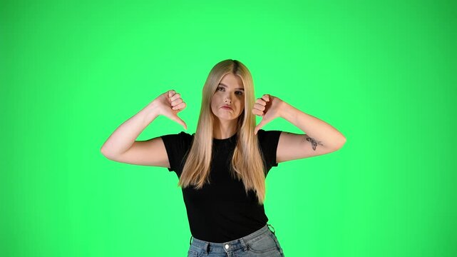 Pretty Blonde Woman Thumbs Down Gesture, Studio Portrait With Green Background