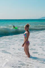 Young woman is covered by a wave in the turquoise sea