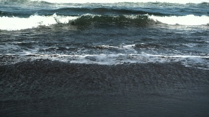 Waves crashing against the shore with a clear blue sky in the background at Parangtritis Beach, Yogyakarta.