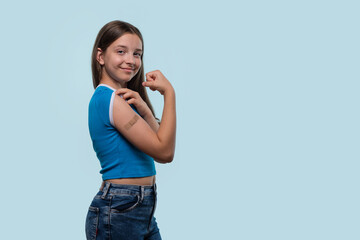 Girl flexing arm and showing bandage after vaccination