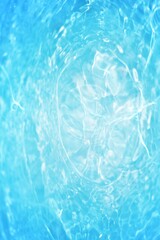 Blue water with ripples on the surface. Defocus blurred transparent blue colored clear calm water surface texture with splashes and bubbles. Water waves with shining pattern texture background