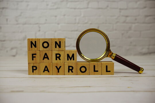 Non Farm Payroll with wooden blocks alphabet letters and magnifying glass on wooden background