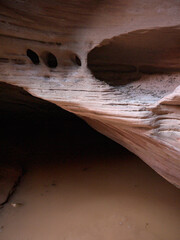 Eroded Buckskin Gulch canyon red rock sandstone walls, mud water in puddle on canyon bed after the...