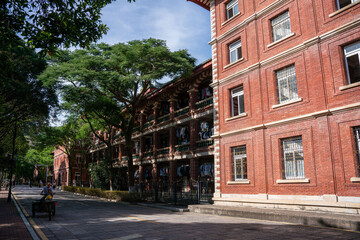 Fototapeta premium A red brick building with green trees on a sunny day, showcasing an elegant urban architectural scene.