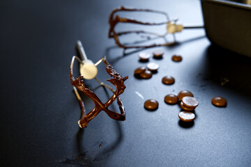 Two whisk with melted chocolate placed with chocolate of dark theme. Selective focus on electric whisk with blurred background. Milk chocolate, chips, still-life food, dessert, and home cook concepts.