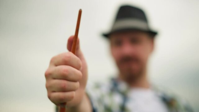 A painter, blurry except for his hand, holds a paintbrush aloft. The brush is in sharp focus, highlighting the moment of artistic engagement against a vague backdrop