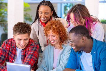 A group of students with laptops sit near the campus and communicate.