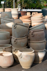 Vertical photo variety of clay pots in different sizes and shapes are neatly stacked outside a garden supply store, perfect for gardening enthusiasts and landscaping projects.  Flower pots and vases
