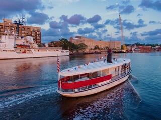 Tourist ferry boat on the Cape Fear River and the riverfront of the Historic District at sunset. Wilmington, North Carolina, United States.
