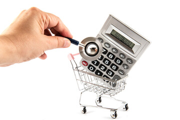 Stethoscope head and calculator in miniature supermarket shopping cart