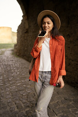 Woman tourist dictating voice message on smartphone while exploring historical site