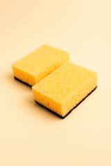 Yellow kitchen sponges for washing dishes on a beige background. Homework. Household work. Washing dishes.