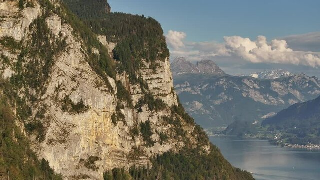 Close-up view of massive stone cliffs towering over Lake Walensee in the Swiss Alps. Drone 4k.