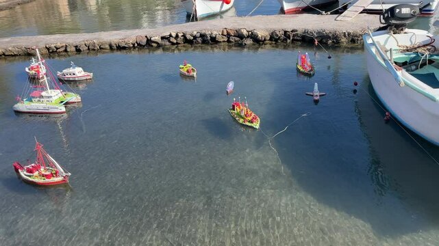 Greece,Arki Island,Model ships swinging slowly on a natural sea pond, footage moves from left to right. some real size fisherman's boats behind the pond and a fisherman's boat on land under trees.