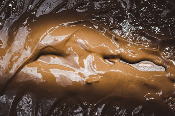 A brown liquid with a brownish color, which appears to be a mixture of chocolate and water. The liquid is spread out and has a thick consistency, giving it a rich and indulgent appearance
