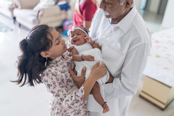 ndian family spending time together, wearing traditional and casual outfits with a baby, a young...
