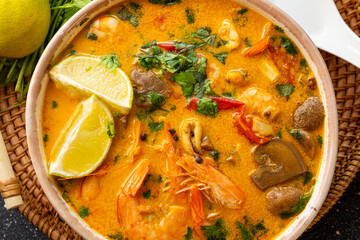 Tom yum soup with shrimp, sea food and lime close up