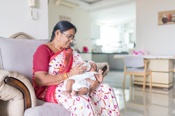 ndian family spending time together, wearing traditional and casual outfits with a baby, a young girl, and grandparents in a high-rise apartment in Kuala Lumpur, Malaysia.