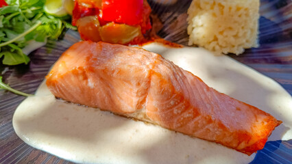 morceau de saumon cuit, sauce, et légumes, en gros plan, dans une assiette