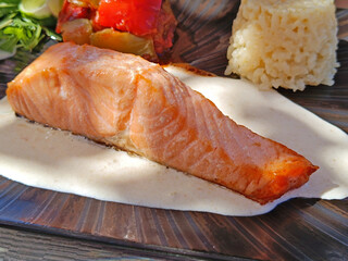 morceau de saumon cuit, sauce, et légumes, en gros plan, dans une assiette