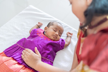 ndian family spending time together, wearing traditional and casual outfits with a baby, a young girl, and grandparents in a high-rise apartment in Kuala Lumpur, Malaysia.