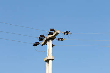 A concrete pole on an electricity transmission line on blue sky background