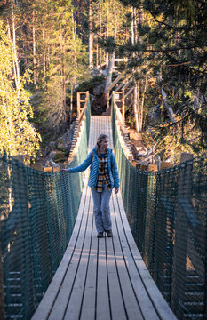 woman in a blue jacket crossing a suspension bridge in Finland