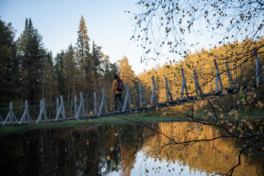 man in a yellow jacket crossing a suspension bridge in Finland